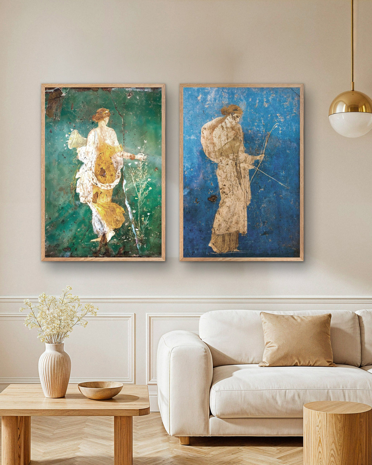 Conjunto de 2 posters de frescos romanos, Flora e Ártemis, com molduras de madeira natural por cima de um sofá numa sala de estar
